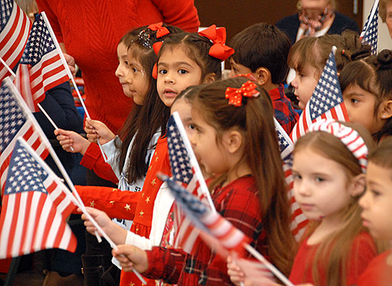 children holding American flags and singing.